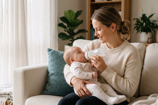 Mother holding baby upright on lap practicing paced bottle feeding with bottle held horizontal